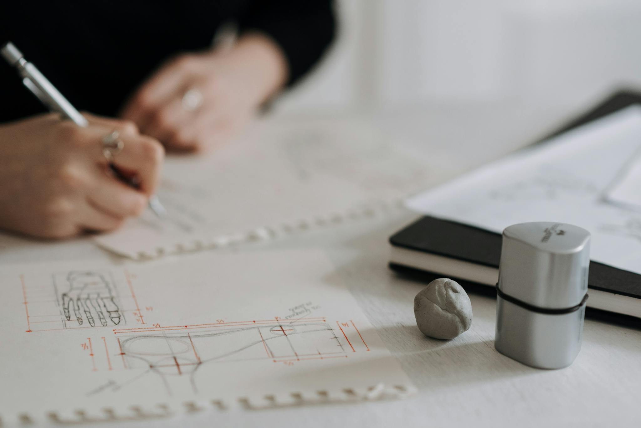 Detailed hand sketching on architectural blueprints with drawing tools and notebook.